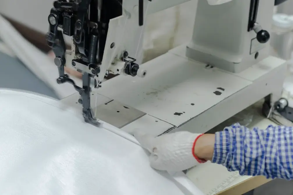 Close-up of an industrial sewing machine stitching FIBC bulk bags.