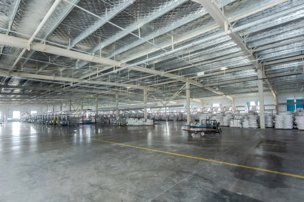 Large FIBC bulk bag manufacturing factory with woven fabric rolls and industrial storage.